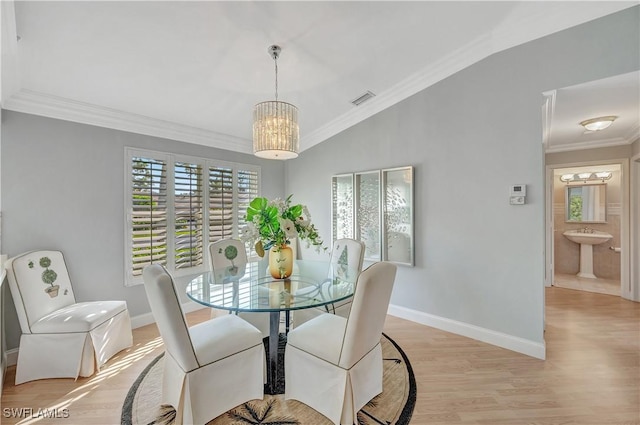 dining area with a chandelier, ornamental molding, light hardwood / wood-style flooring, and lofted ceiling