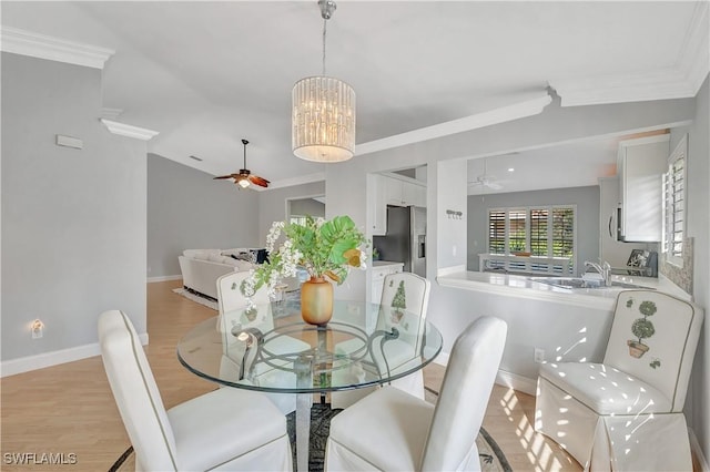 dining room featuring ceiling fan with notable chandelier, light hardwood / wood-style flooring, lofted ceiling, and sink