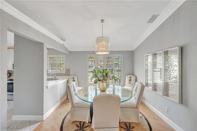 dining room with ornamental molding, light wood-type flooring, sink, and a chandelier