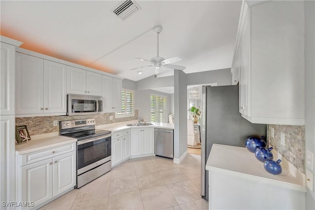 kitchen featuring decorative backsplash, stainless steel appliances, white cabinets, and light tile patterned flooring