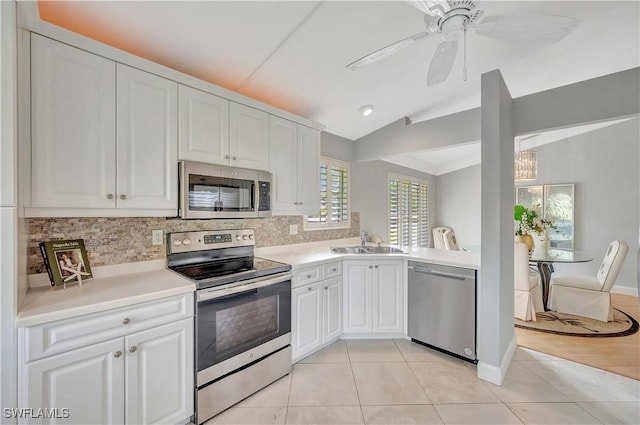 kitchen with lofted ceiling, sink, appliances with stainless steel finishes, light tile patterned flooring, and white cabinetry