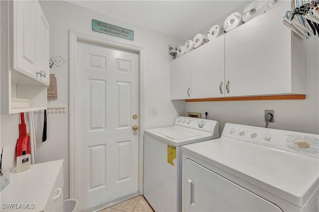 laundry area featuring washer and dryer, light tile patterned floors, and cabinets