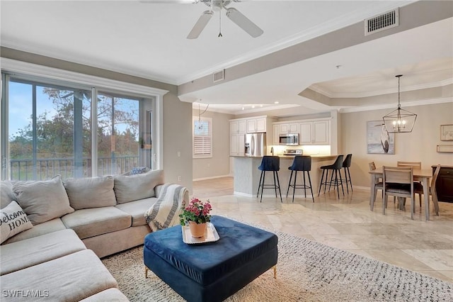 living room with ceiling fan with notable chandelier, a raised ceiling, and crown molding