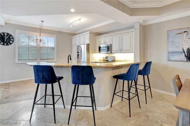 kitchen featuring a kitchen breakfast bar, rail lighting, decorative light fixtures, appliances with stainless steel finishes, and a notable chandelier