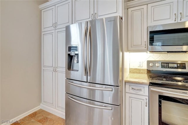 kitchen with light stone countertops, backsplash, stainless steel appliances, and white cabinetry