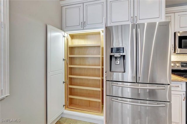 kitchen with white cabinets, decorative backsplash, and stainless steel appliances