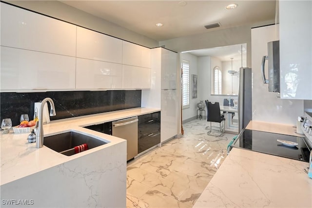 kitchen with backsplash, white cabinets, sink, light stone countertops, and stainless steel appliances