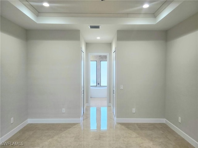 unfurnished room featuring a raised ceiling and ornamental molding