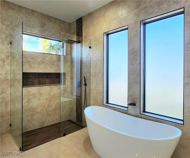 bathroom with tile walls and independent shower and bath