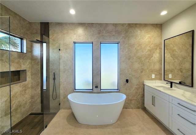 bathroom with tile patterned flooring, vanity, shower with separate bathtub, and tile walls