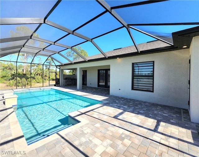 view of swimming pool with glass enclosure and a patio