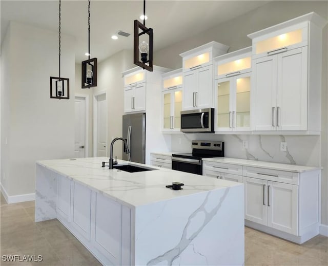 kitchen featuring pendant lighting, a center island with sink, appliances with stainless steel finishes, light stone counters, and white cabinetry