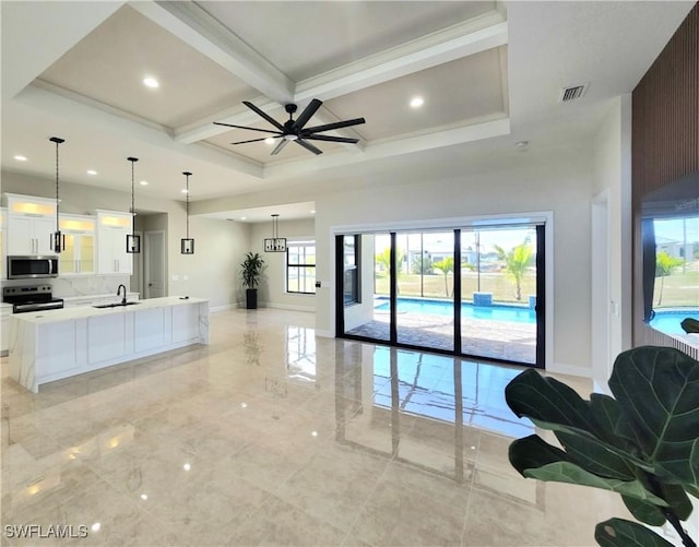 living room with ceiling fan, sink, beamed ceiling, and plenty of natural light