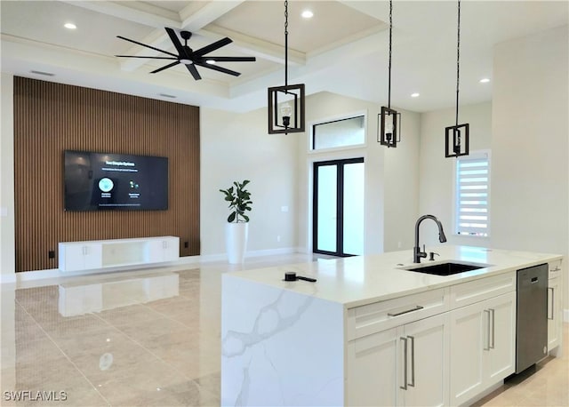 kitchen with light stone countertops, sink, decorative light fixtures, a center island with sink, and white cabinetry