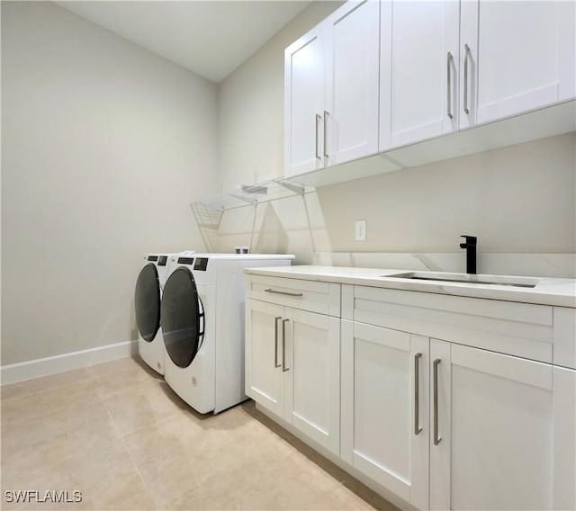 clothes washing area with light tile patterned flooring, cabinets, sink, and washing machine and clothes dryer