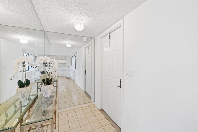 corridor featuring a textured ceiling and light tile patterned flooring