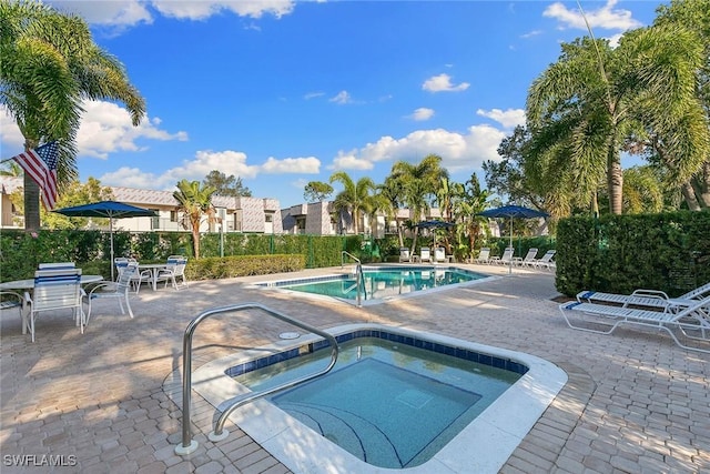 pool with a patio and a hot tub