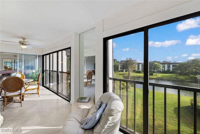 sunroom / solarium featuring ceiling fan and a water view