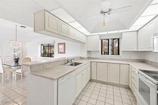 kitchen with white appliances, visible vents, a peninsula, a sink, and a raised ceiling