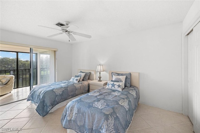 bedroom featuring a ceiling fan, a textured ceiling, a closet, light tile patterned flooring, and access to exterior