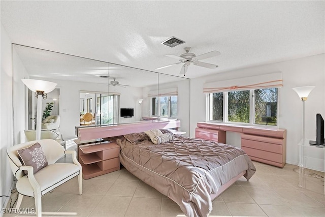 bedroom featuring light tile patterned floors, visible vents, a textured ceiling, and ceiling fan