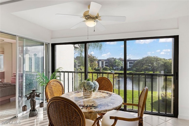 sunroom with ceiling fan and a water view