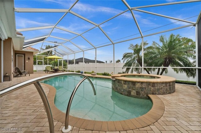 view of pool featuring a patio area, a pool with connected hot tub, and glass enclosure