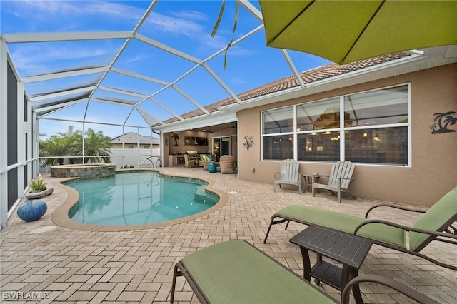 view of swimming pool featuring glass enclosure, a pool with connected hot tub, a patio area, and ceiling fan