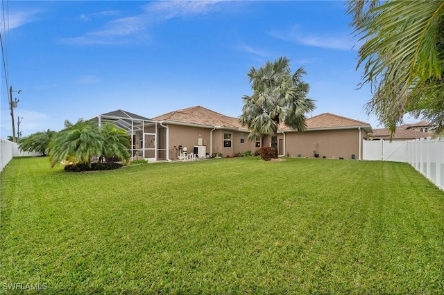 rear view of house featuring stucco siding, a lawn, a tile roof, a fenced backyard, and a lanai