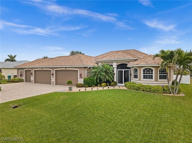 mediterranean / spanish house with a tiled roof, an attached garage, decorative driveway, and a front yard