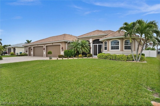 mediterranean / spanish-style home featuring a garage, stucco siding, a tile roof, and a front yard