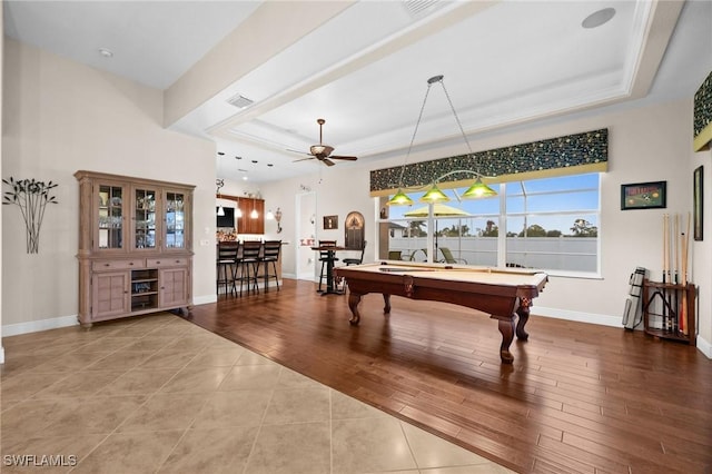 recreation room featuring wood finished floors, a raised ceiling, visible vents, and baseboards