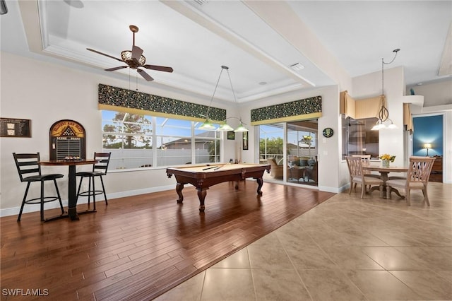 recreation room featuring a tray ceiling, wood finished floors, and baseboards