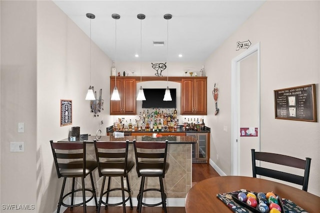 bar featuring dark wood-style floors, wet bar, visible vents, and hanging light fixtures