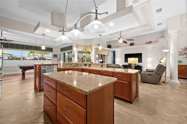 kitchen with a kitchen island, visible vents, stainless steel dishwasher, brown cabinetry, and a raised ceiling