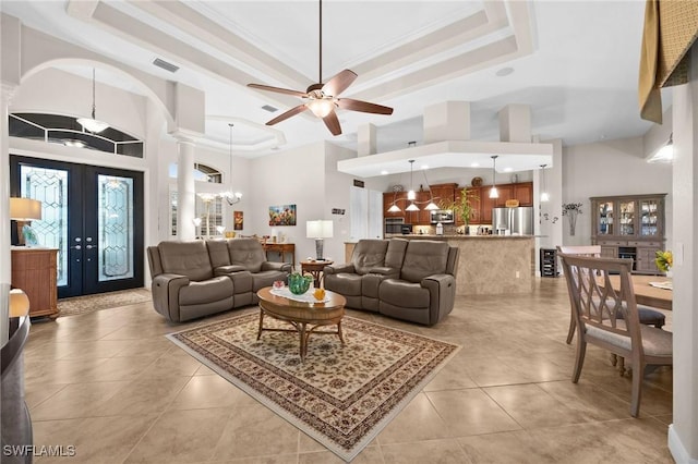 living area with ornate columns, ornamental molding, a raised ceiling, and light tile patterned flooring