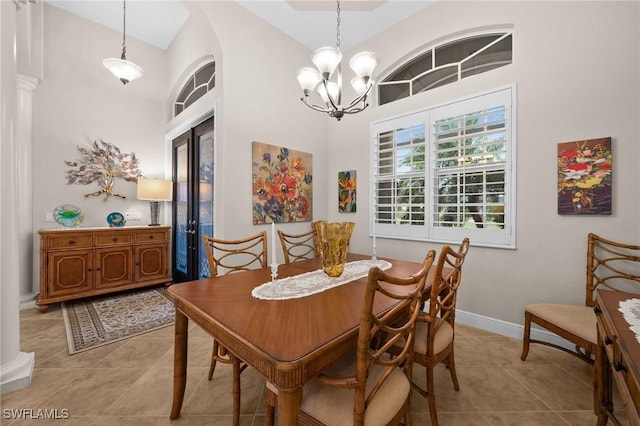 dining room featuring arched walkways, light tile patterned floors, an inviting chandelier, high vaulted ceiling, and baseboards