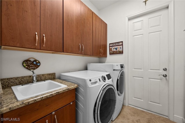 clothes washing area featuring cabinet space, light tile patterned floors, a sink, and washing machine and clothes dryer