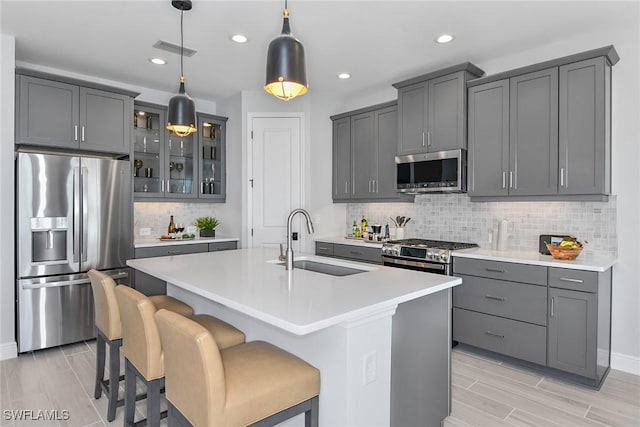 kitchen featuring pendant lighting, an island with sink, stainless steel appliances, and sink