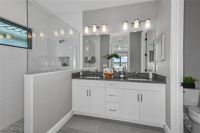 bathroom featuring a tile shower, vanity, toilet, and tile patterned floors