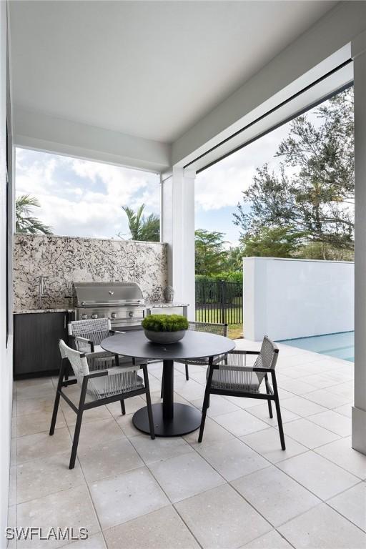 6705 Newport Rd, Naples, FL 34109 - view of patio featuring a grill, fence, and an outdoor kitchen