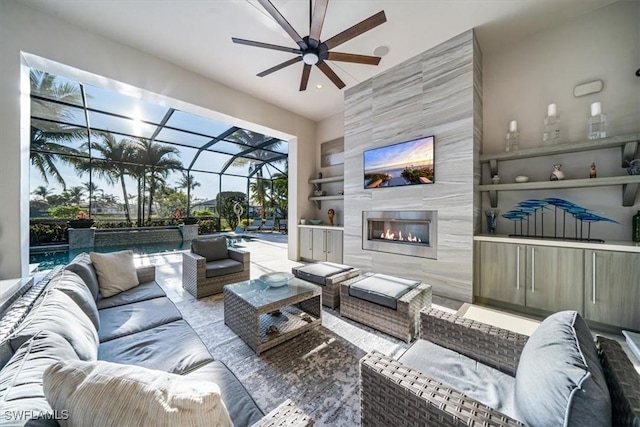 living room featuring an outdoor fireplace and ceiling fan