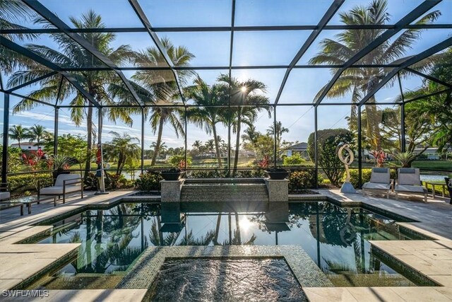 pool at dusk featuring a patio, glass enclosure, and an in ground hot tub