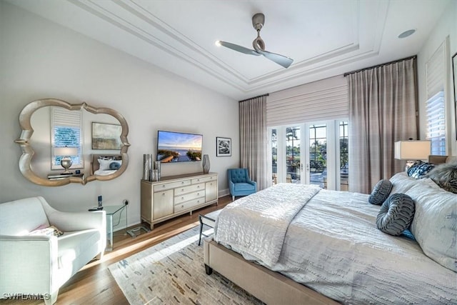 bedroom featuring access to outside, hardwood / wood-style flooring, french doors, a tray ceiling, and ceiling fan