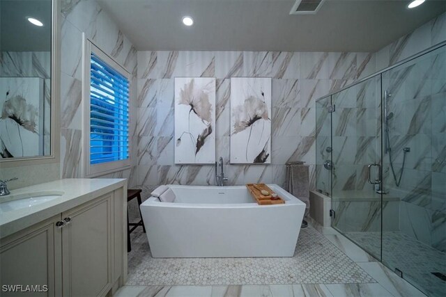 bathroom featuring a raised ceiling, tile walls, independent shower and bath, vanity, and a chandelier