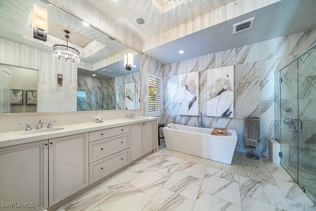 bathroom with tile walls, shower with separate bathtub, a chandelier, and vanity