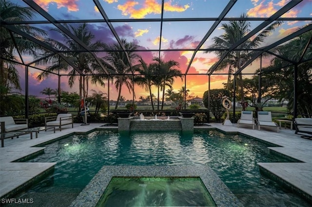 pool at dusk featuring pool water feature, a lanai, an in ground hot tub, and a patio