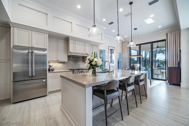 kitchen with beverage cooler, a kitchen island with sink, range, stainless steel fridge, and pendant lighting