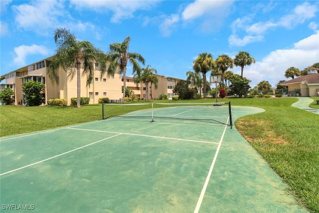 view of tennis court featuring a lawn and basketball hoop