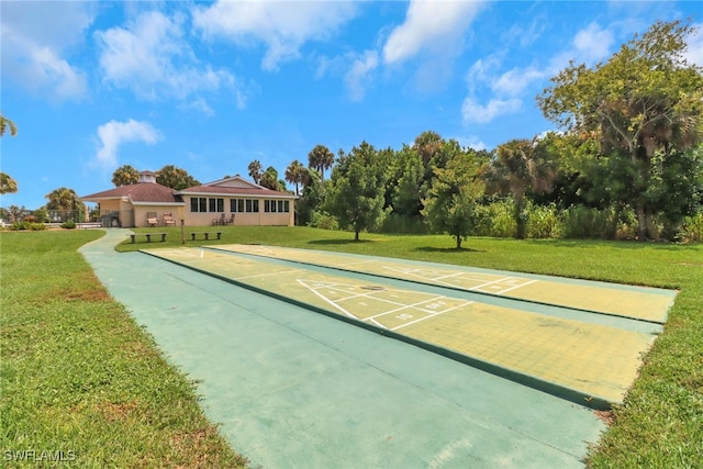 view of property's community featuring shuffleboard and a yard